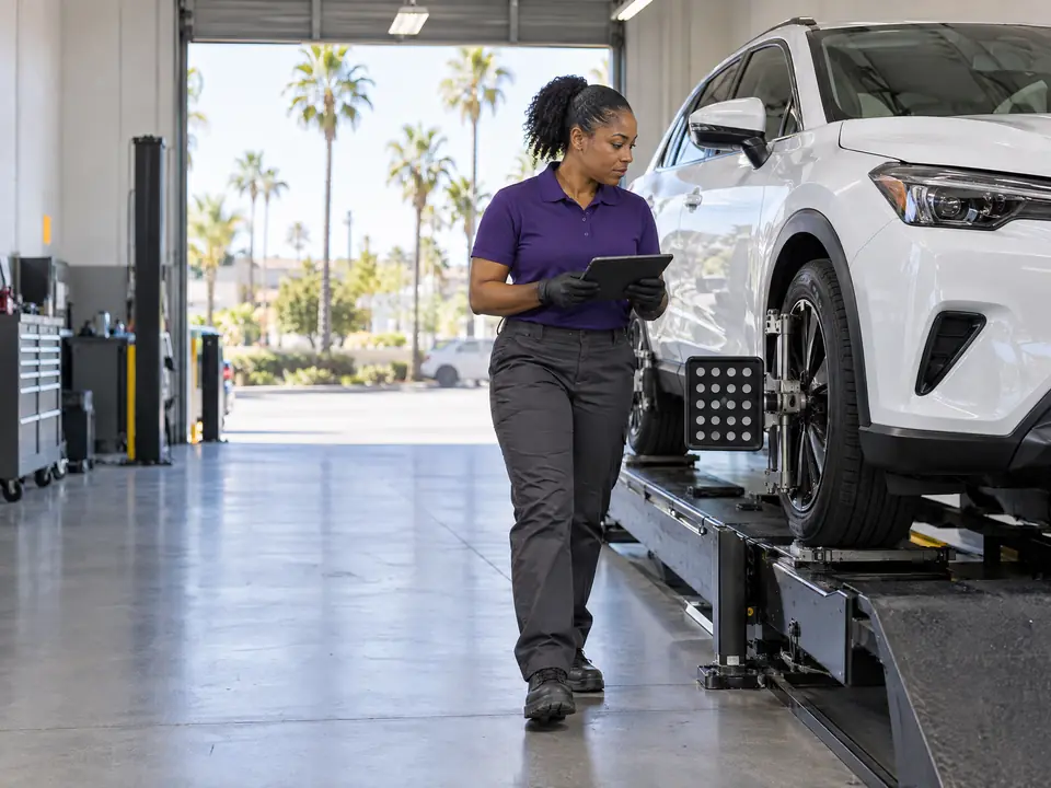 A technician with a tablet beside a crossover on an alignment rack